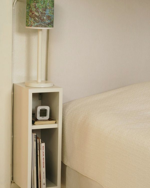 The finished white cube bedside table fixed to the wall beside a bed