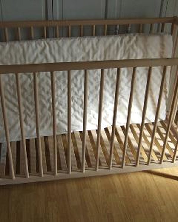 The cot base still assembled, standing on a wooden floor
