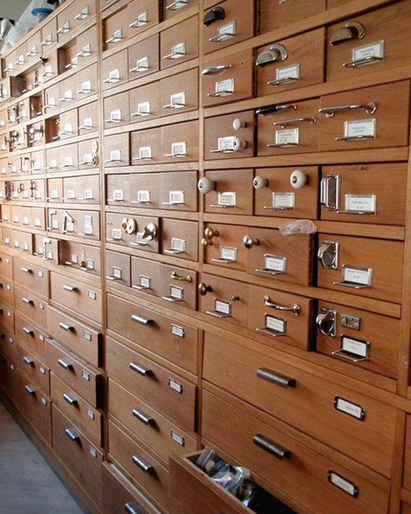 A wall of small wooden drawers with metal label frames in the restoration shop