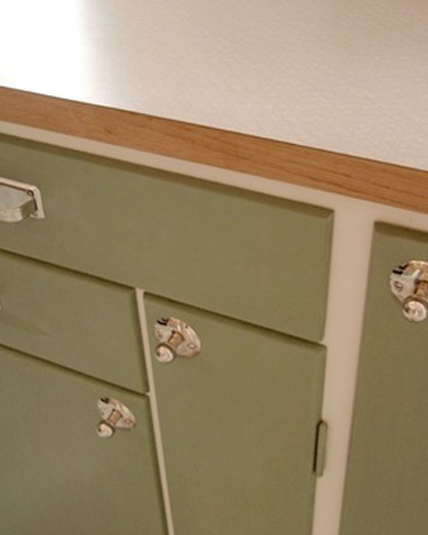 A green painted kitchen unit with cup handles and a wooden worktop