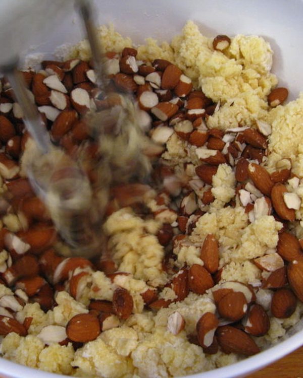 Chopped almonds being folded into the pale batter