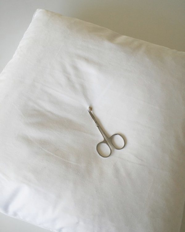 Small scissors on the folded white pillow cover