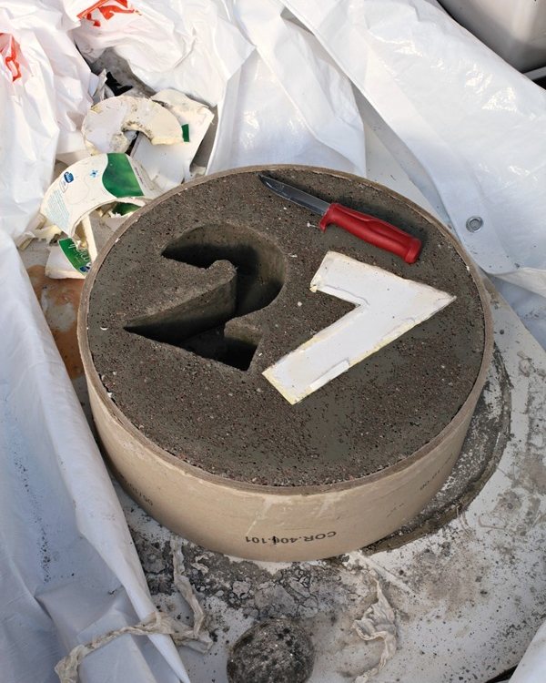 The number 27 set face down in the filled mould, curing under plastic