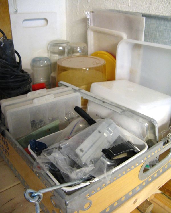 A shallow bin of clamps and hand tools pulled out from under the workbench