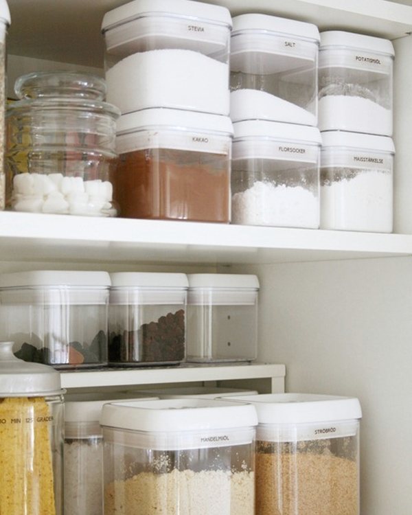 Clear containers of dry goods in two rows on a wire shelf riser