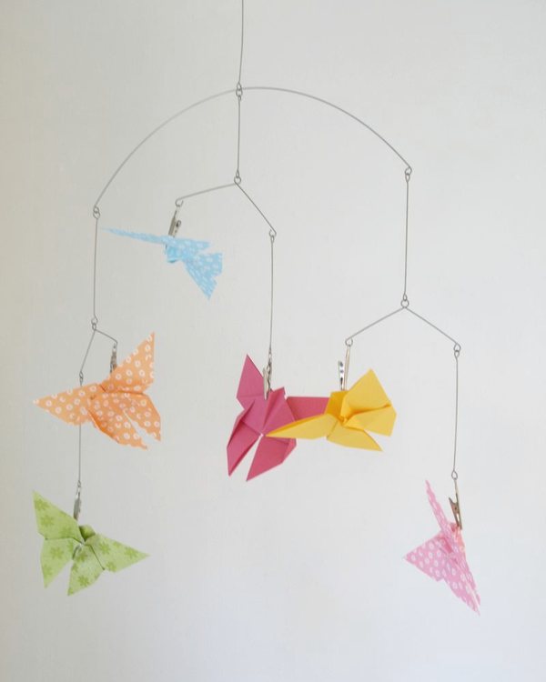 The mobile of folded paper butterflies hanging against a white wall