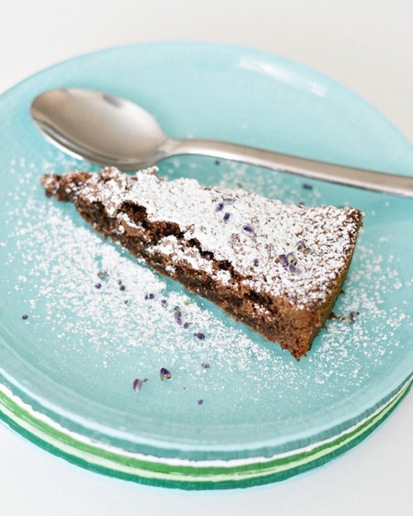 A slice of tart with a spoon on the stacked painted plates