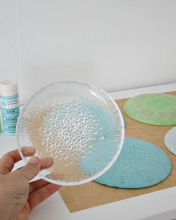 Holding a glass plate above the paint pots and two finished plates