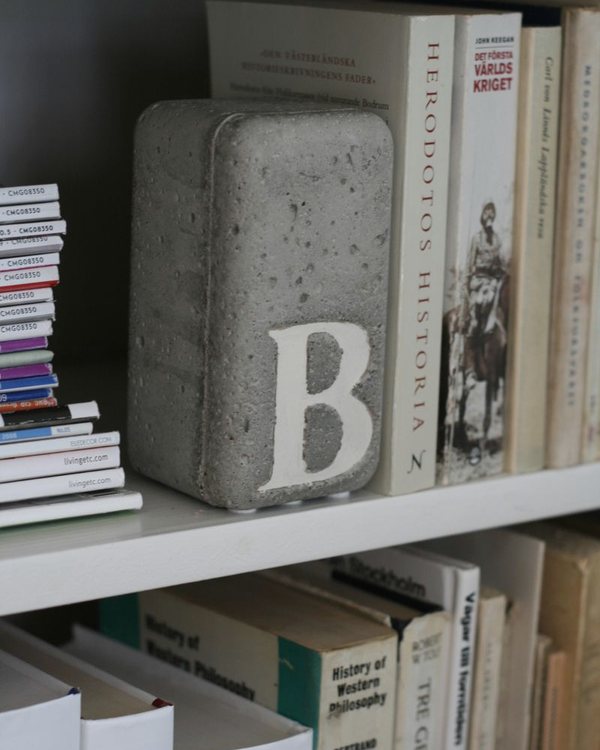 The finished concrete bookend holding books on a white shelf