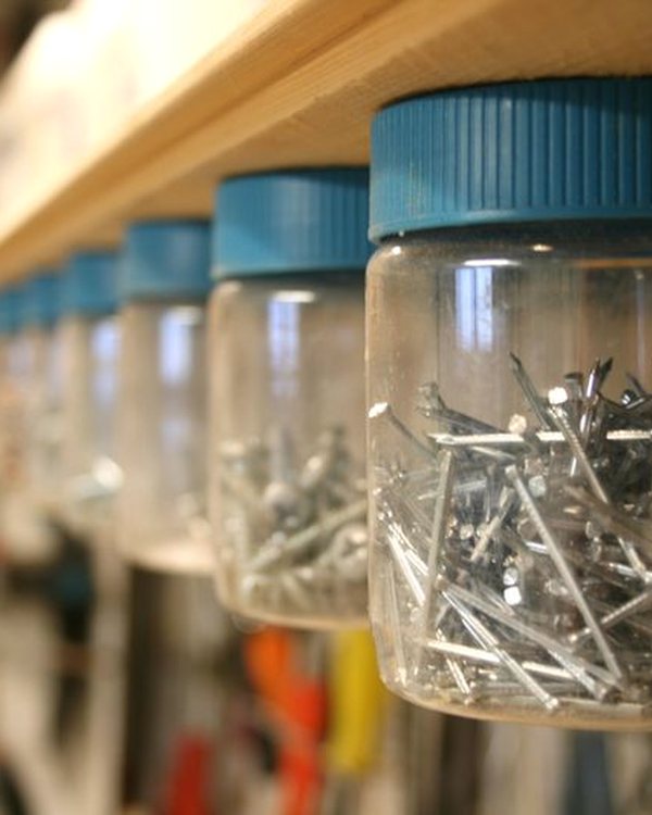 A row of jars hanging under the shelf, filled with nails