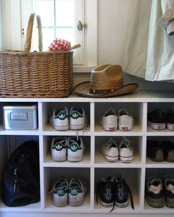 The finished white shoe cubby full of shoes, a basket and hat on top