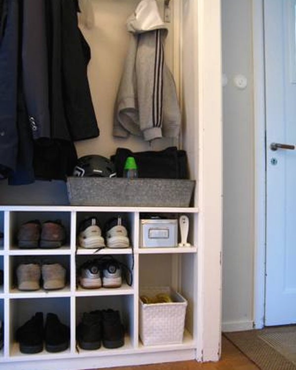 The shoe cubby in the hall beside the door, coats hanging above it