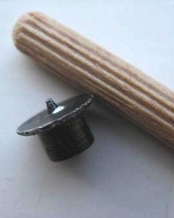 A wooden dowel and a screw cap on a white surface