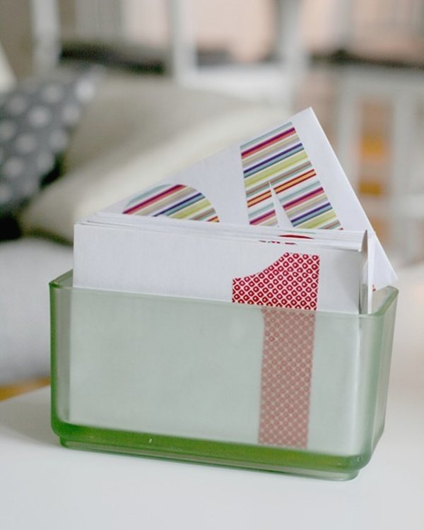 Numbered white envelopes standing in a green glass container