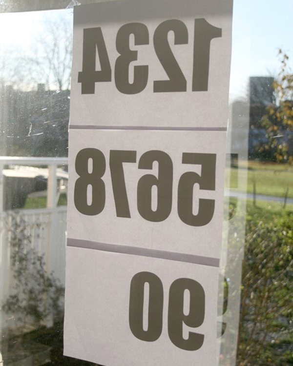 Sheets of printed numbers taped to a window, reversed