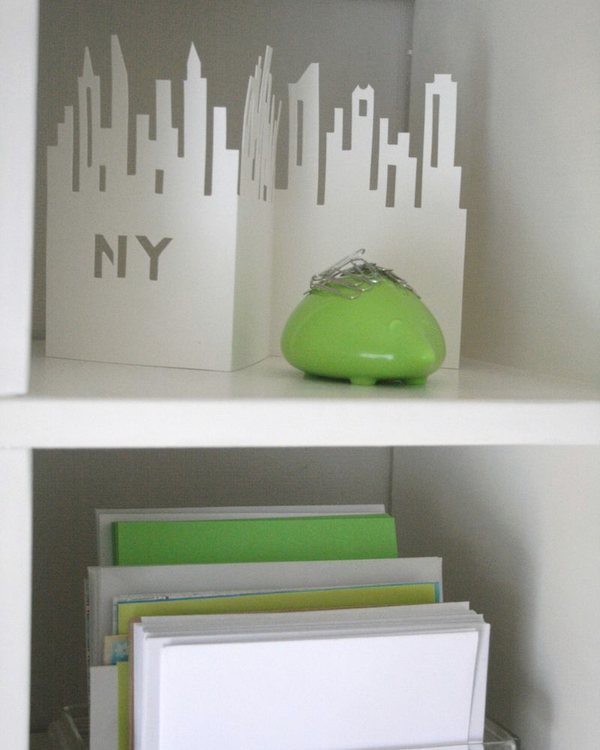 A white cut-out skyline ornament on a shelf above filed papers