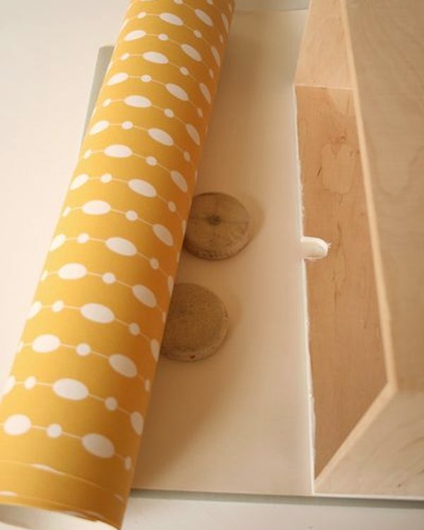 A roll of yellow patterned wallpaper beside the drawer