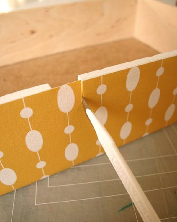 Trimming the wallpaper to the drawer edge with a knife